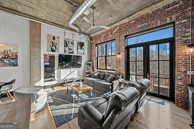 living room featuring a wood stove, plenty of natural light, wood finished floors, and brick wall