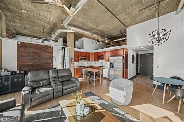 living room with wood finished floors, a towering ceiling, and a chandelier