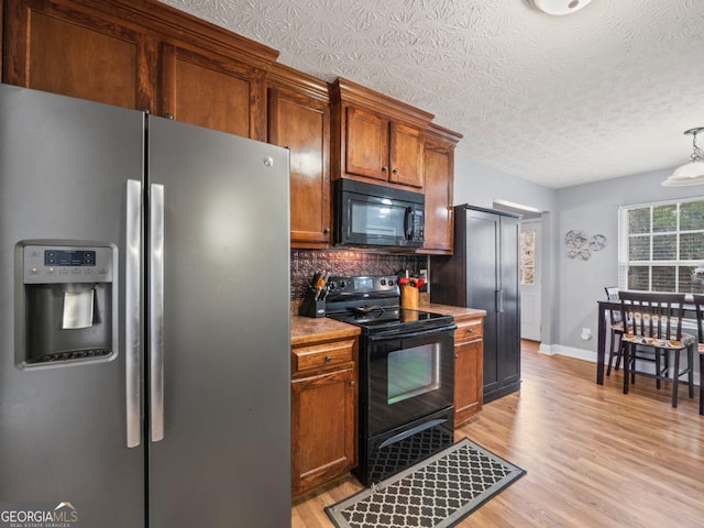 kitchen featuring decorative backsplash, black appliances, light wood-style floors, and a textured ceiling