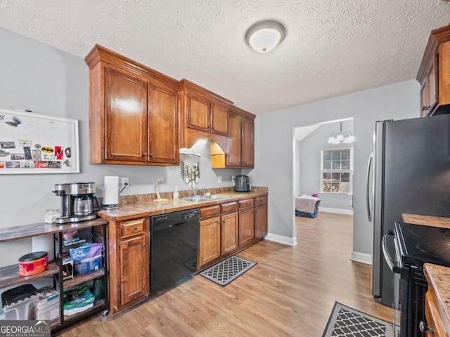 kitchen featuring brown cabinets, black appliances, light wood-type flooring, and a sink