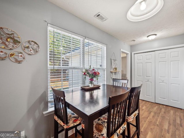 dining space featuring light wood-style flooring, visible vents, and a textured ceiling