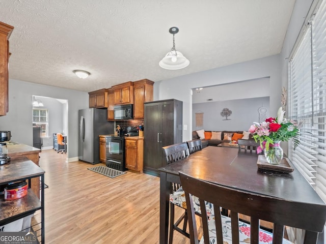 dining room with baseboards, light wood finished floors, and a textured ceiling