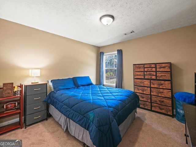 bedroom featuring visible vents, light colored carpet, and a textured ceiling