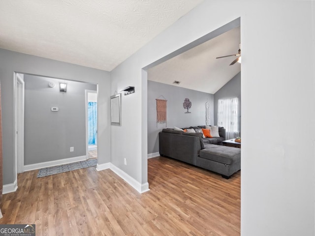 foyer featuring baseboards, light wood-style floors, lofted ceiling, and a ceiling fan