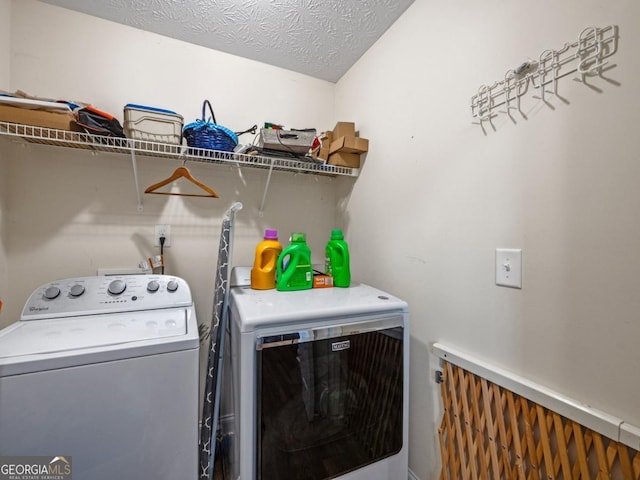 washroom featuring washing machine and clothes dryer, laundry area, and a textured ceiling