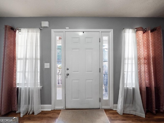 entryway featuring baseboards, a textured ceiling, and wood finished floors