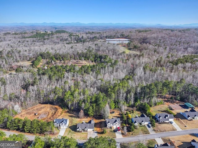 birds eye view of property featuring a mountain view, a residential view, and a wooded view