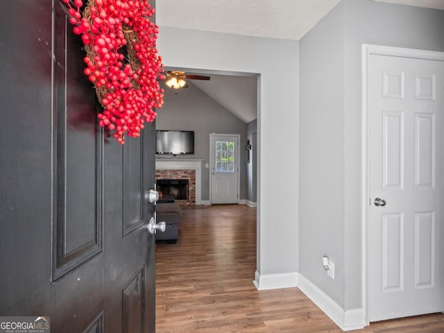 entryway featuring a fireplace, baseboards, a ceiling fan, and wood finished floors