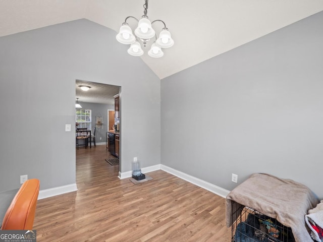 dining space with vaulted ceiling, a notable chandelier, light wood-style floors, and baseboards