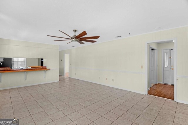 unfurnished living room with visible vents, a ceiling fan, crown molding, tile patterned flooring, and baseboards