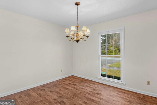 interior space featuring a notable chandelier, wood finished floors, and baseboards