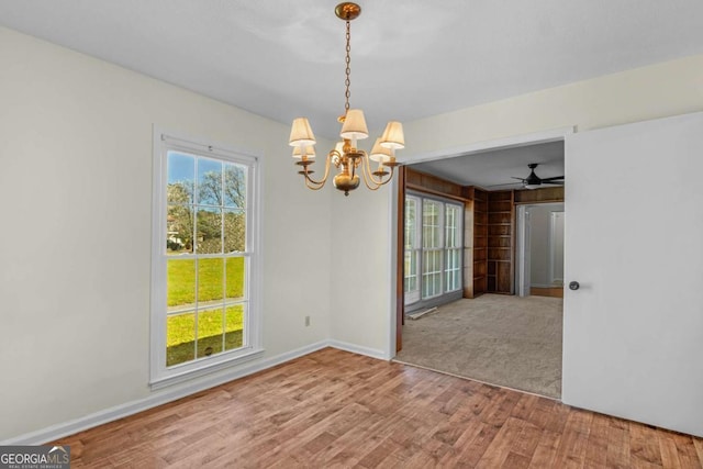 spare room with an inviting chandelier, wood finished floors, and baseboards