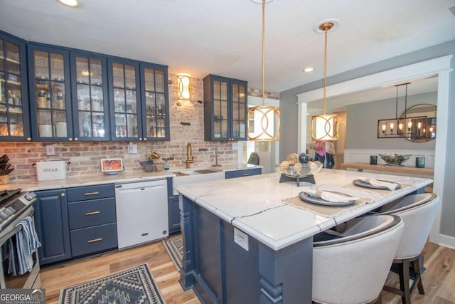 kitchen with blue cabinetry, a kitchen island, glass insert cabinets, dishwasher, and stainless steel range