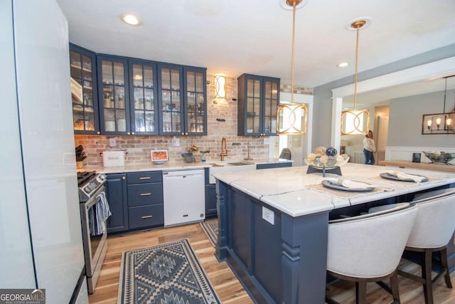 kitchen featuring a center island, white dishwasher, stainless steel gas stove, blue cabinets, and a sink