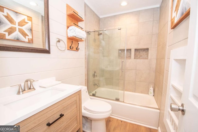 full bath featuring vanity, toilet, wood finished floors, and shower / bath combination with glass door