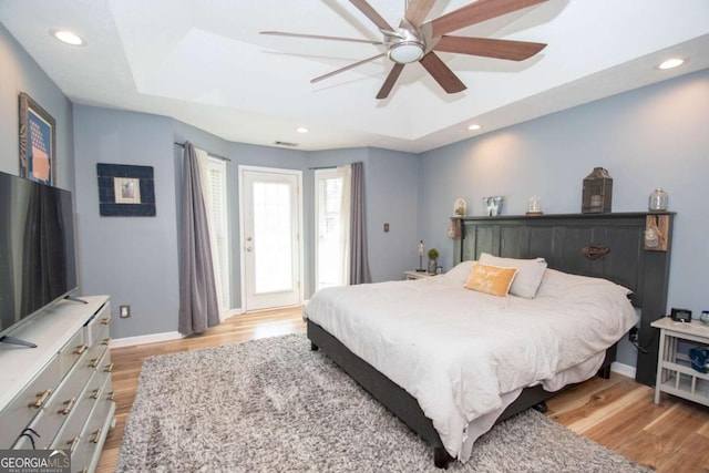 bedroom with visible vents, baseboards, a tray ceiling, recessed lighting, and light wood-type flooring