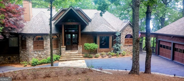912 Mcelroy Mountain Dr, Big Canoe, GA 30143 - view of front of property featuring stone siding, asphalt driveway, a shingled roof, a chimney, and a garage