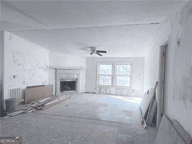 unfurnished living room with visible vents, a ceiling fan, a fireplace, and a textured ceiling