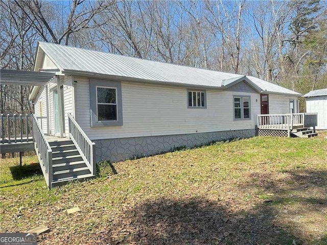 view of property exterior with a deck, a lawn, and metal roof