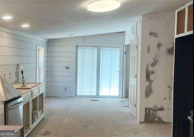 hall with vaulted ceiling and a textured ceiling