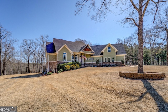 view of front of property featuring stone siding, covered porch, and a front yard