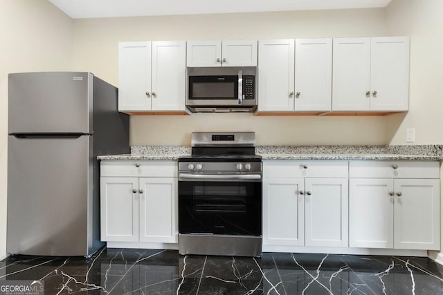 kitchen featuring stainless steel appliances, light stone countertops, marble finish floor, and white cabinets