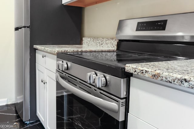 kitchen featuring white cabinetry, light stone countertops, and stainless steel range with electric cooktop