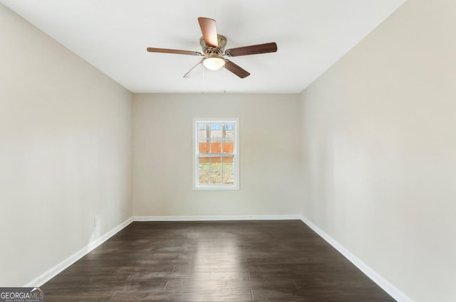 spare room with dark wood finished floors, a ceiling fan, and baseboards