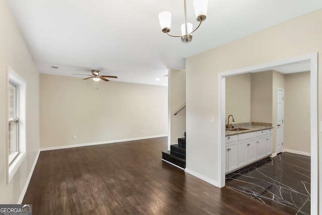 unfurnished living room with dark wood finished floors, stairs, baseboards, and a sink