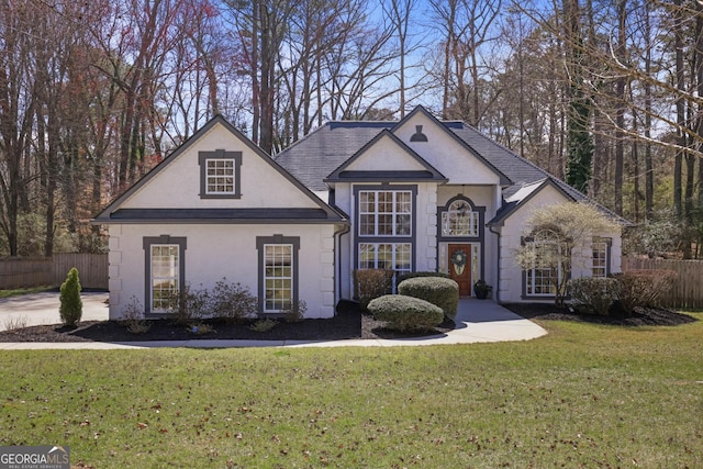 view of front of property with a front yard, fence, and stucco siding