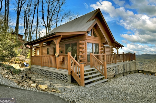 exterior space with log siding, a wooden deck, and metal roof