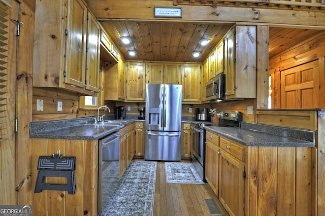 kitchen with dark countertops, stainless steel appliances, wood ceiling, and a sink