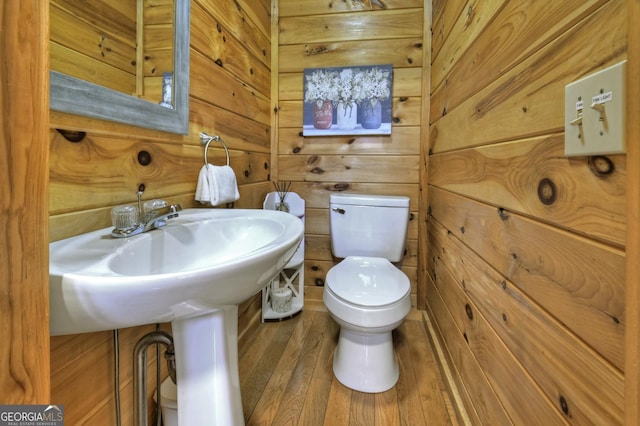 bathroom with toilet, wood finished floors, and wooden walls