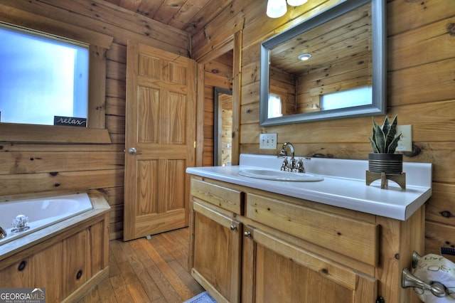 full bathroom featuring wood walls, wood ceiling, hardwood / wood-style floors, a bath, and vanity