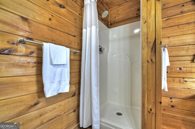 full bathroom with a shower stall and wood walls