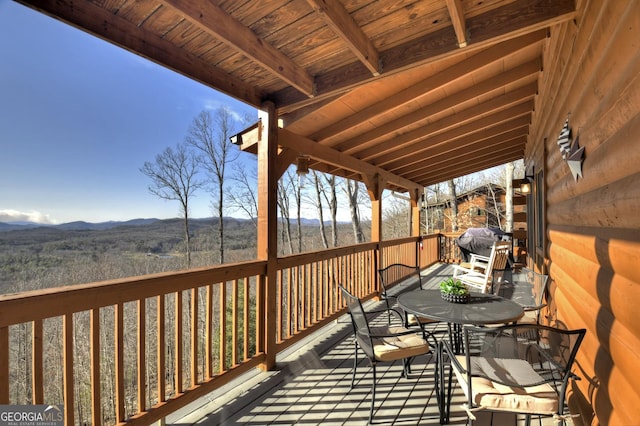 wooden deck featuring outdoor dining area, a mountain view, and grilling area