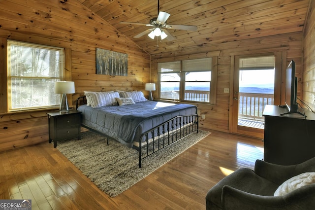 bedroom with access to outside, multiple windows, wood-type flooring, and vaulted ceiling