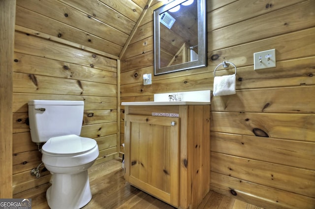 bathroom with toilet, wood finished floors, and wood walls