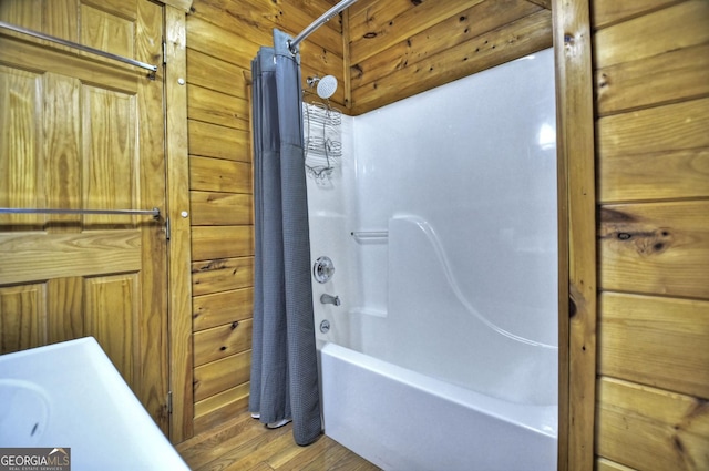 bathroom with wood finished floors, shower / bath combo, and wood walls