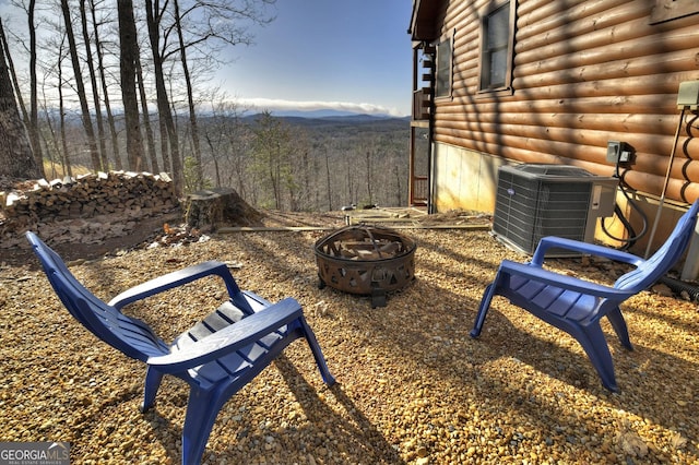 view of yard featuring central air condition unit, a view of trees, a mountain view, and an outdoor fire pit