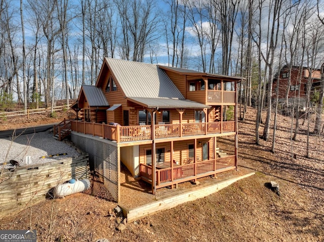 back of property featuring metal roof, a balcony, and a wooden deck