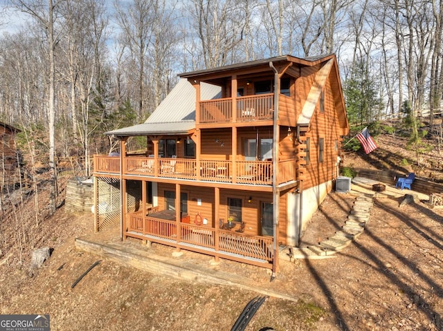 view of front of house featuring central air condition unit, log exterior, driveway, and metal roof