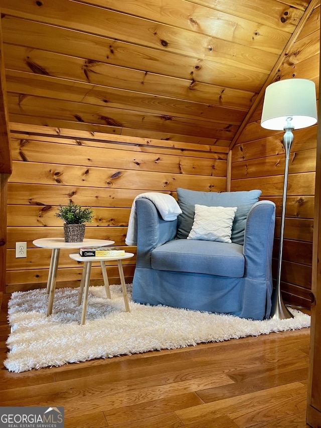 living area featuring lofted ceiling, wooden walls, wood ceiling, and wood finished floors