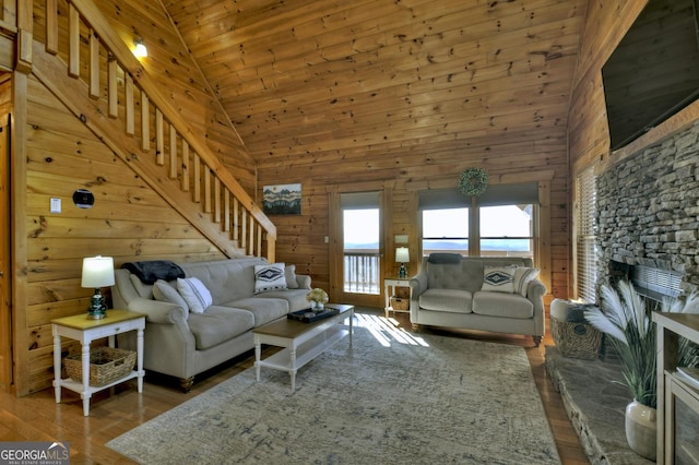 living area with stairway, wood walls, wood ceiling, wood finished floors, and high vaulted ceiling