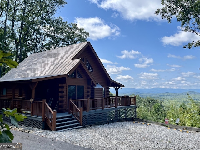 cabin featuring log exterior, a mountain view, and metal roof