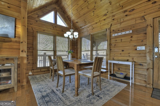 dining room with wooden walls, wood ceiling, hardwood / wood-style floors, an inviting chandelier, and high vaulted ceiling