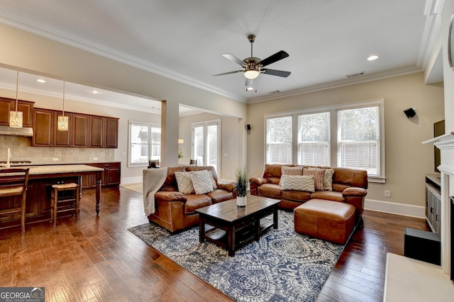 living room featuring visible vents, dark wood finished floors, a fireplace, and ornamental molding