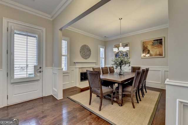 dining area featuring dark wood finished floors, a chandelier, wainscoting, and ornamental molding