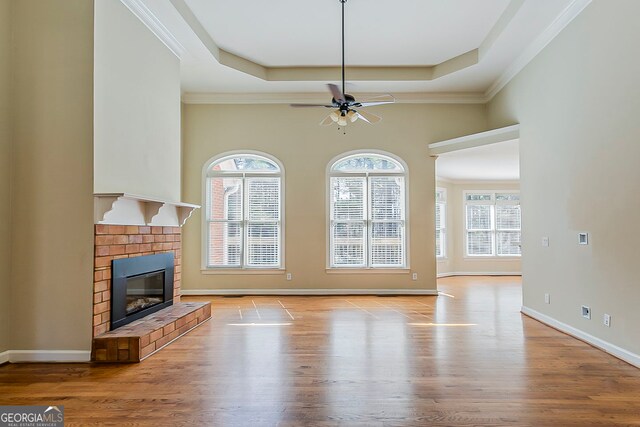 1621 Annapolis Way, Grayson, GA 30017 - unfurnished living room with a brick fireplace, ceiling fan, baseboards, a tray ceiling, and wood finished floors