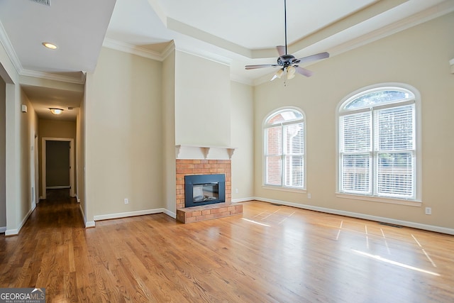 1621 Annapolis Way, Grayson, GA 30017 - unfurnished living room with ornamental molding, a tray ceiling, light wood finished floors, baseboards, and a brick fireplace